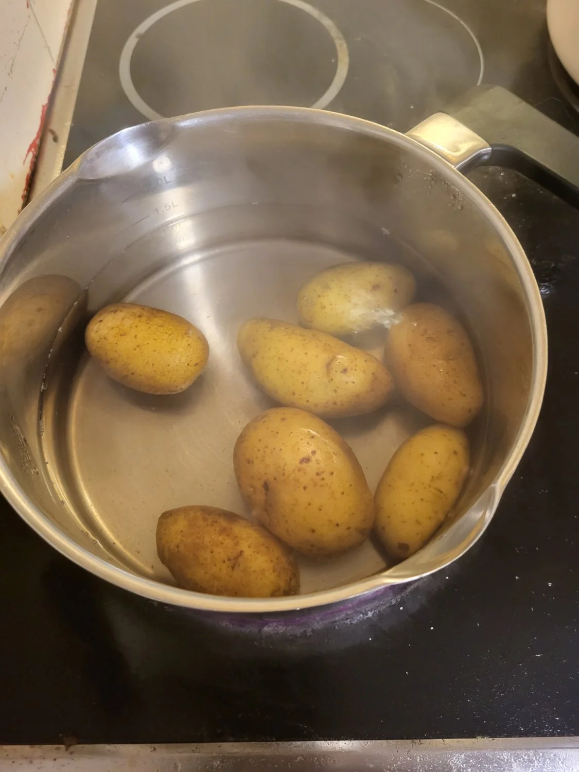 Kettle with potatoes and water. The temperature has been reduced to a simmer.