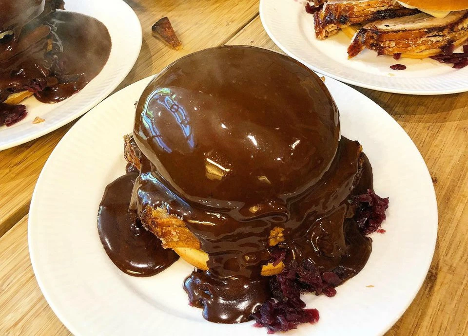 Burger swimming in gravy. The bun is coated making into a diet of gravy dome.