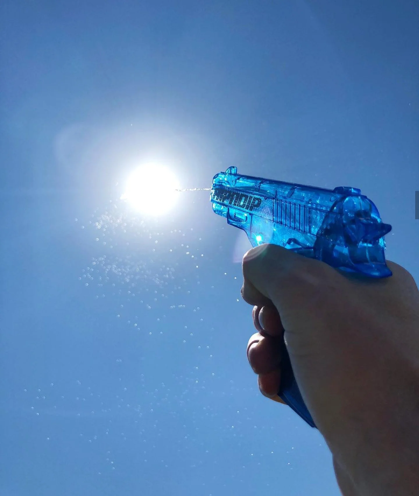 Person firing a water pistol at the sun