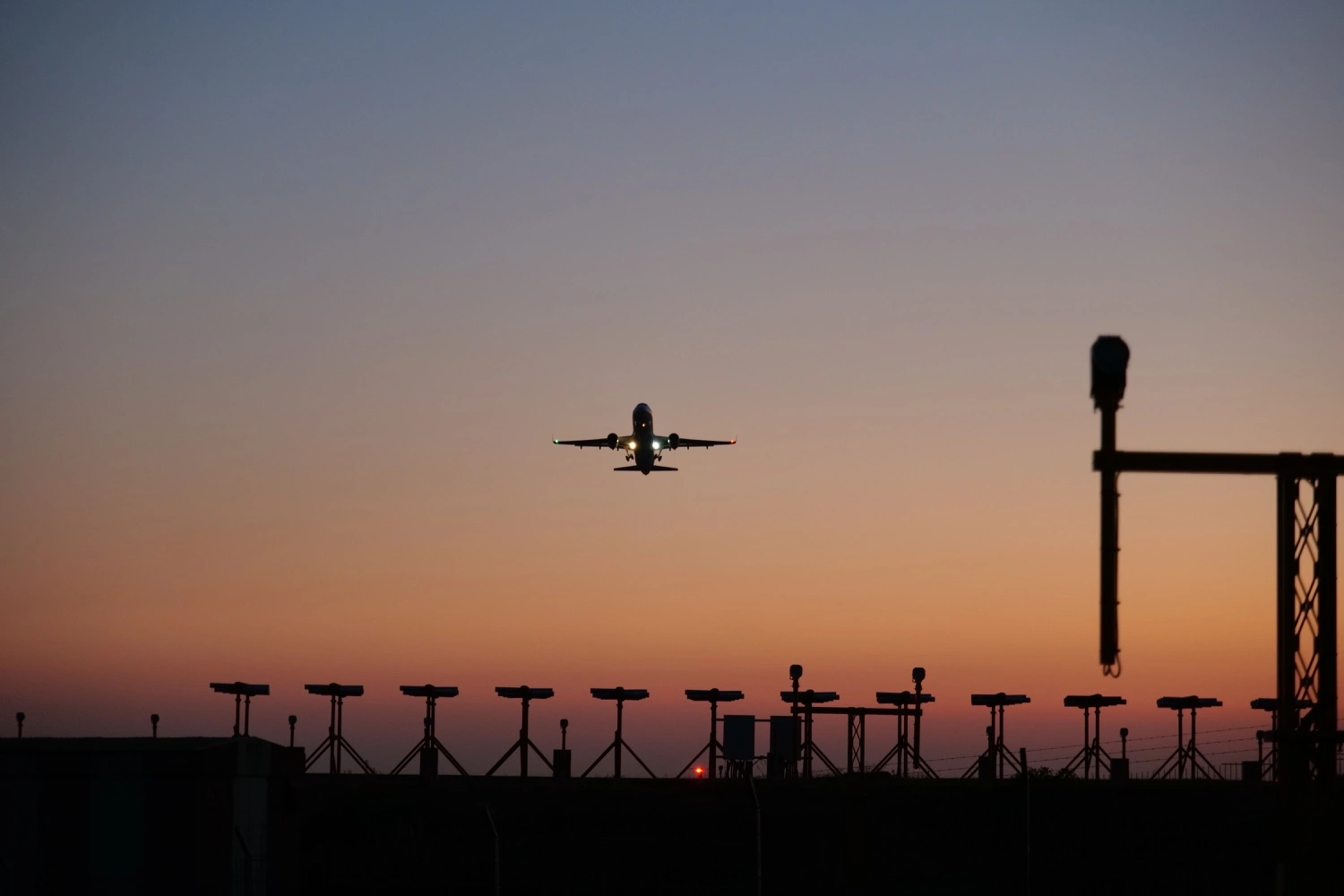 An aircraft taking off toward the camera with a sunset in the background