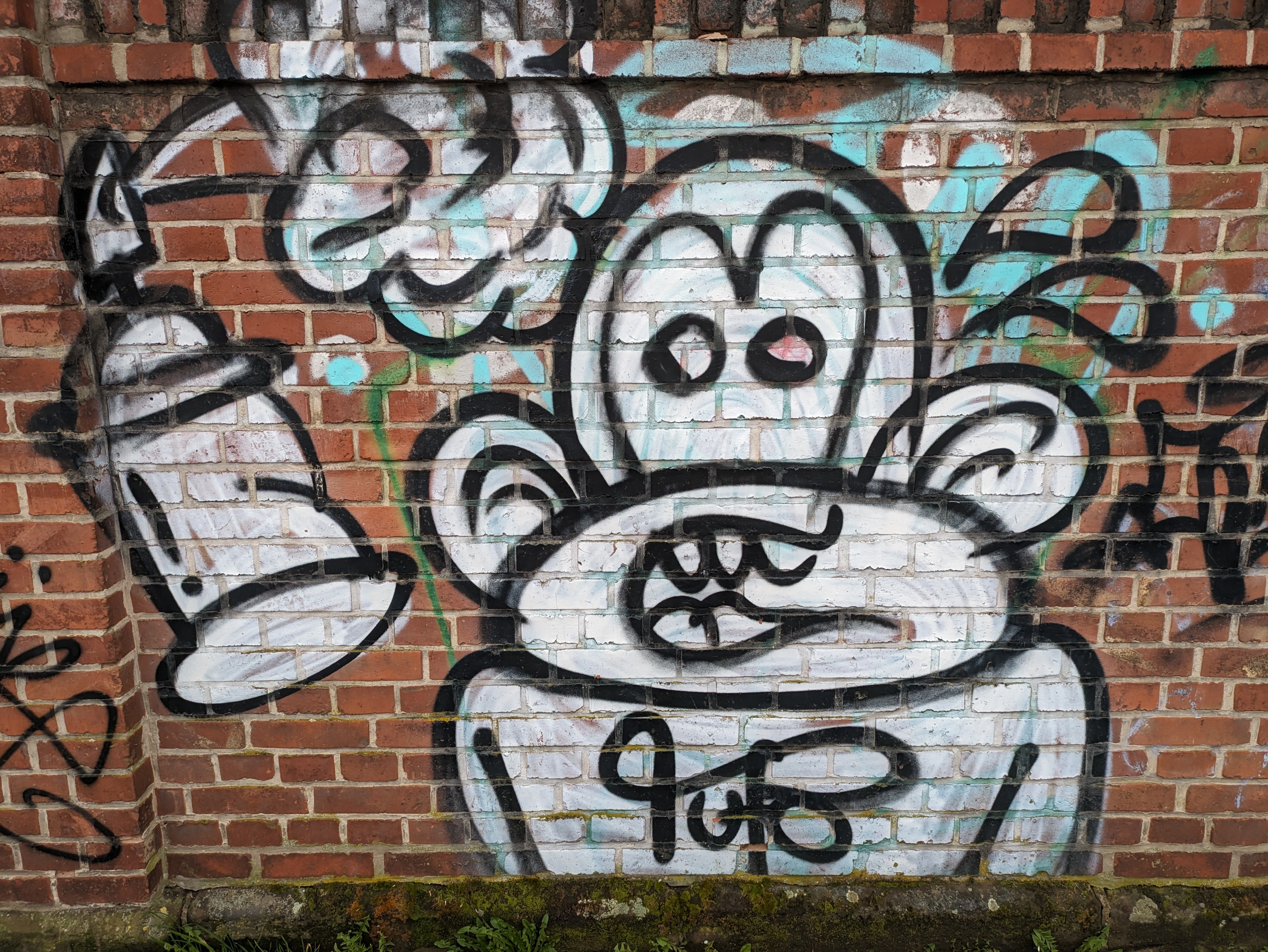 monkey that looks suprised or shocked with a spray can left of it. sprayed with white and black on a red and brown brick wall