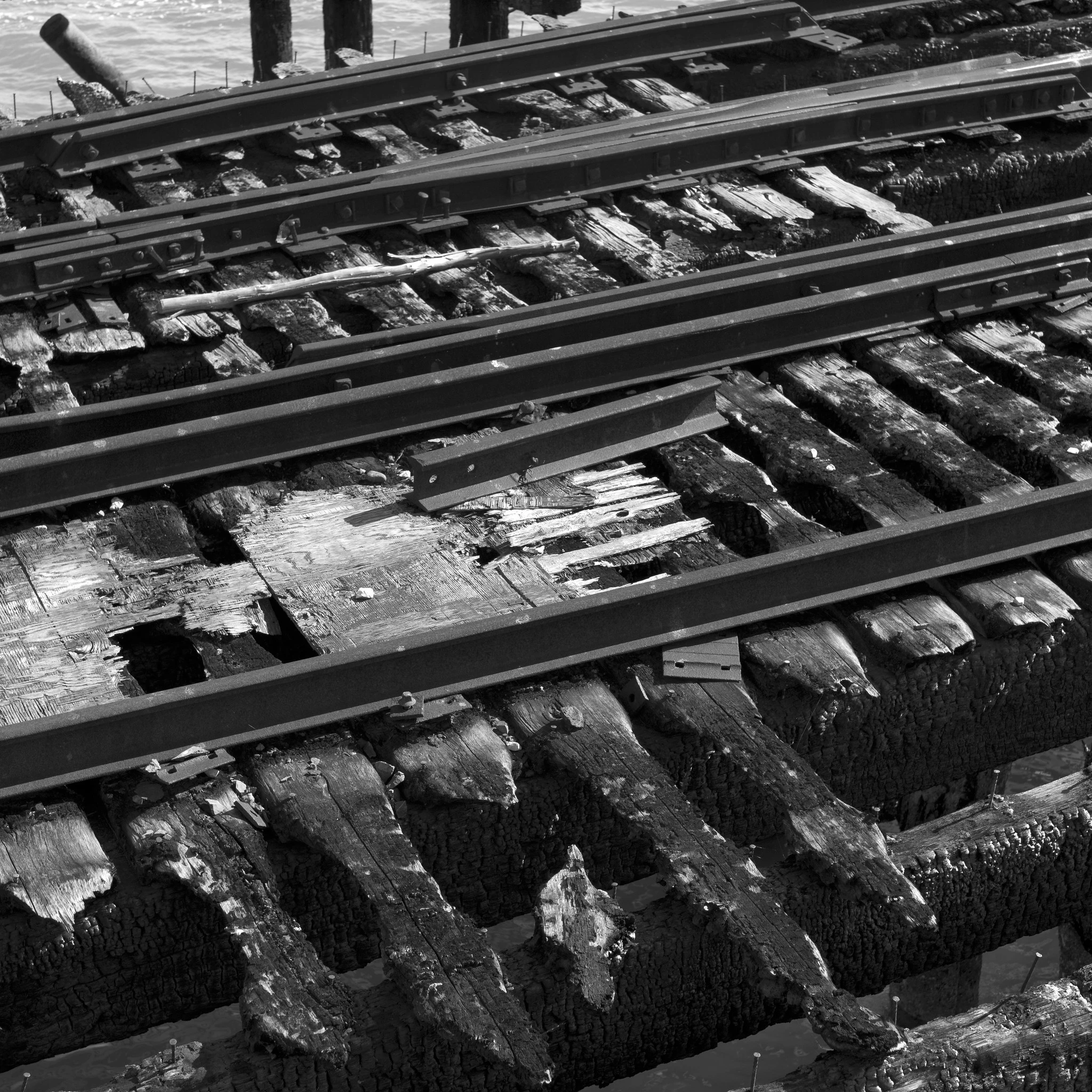 Detail of charred railroad tracks and ties on a carfloat slip, running diagonally across the frame.