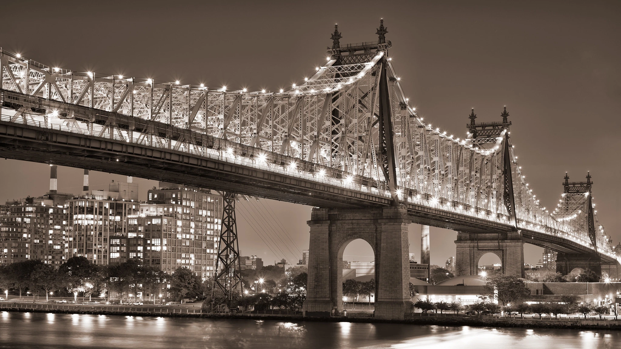 A large cantilever bridge, illuminated along it's superstructure, at night.