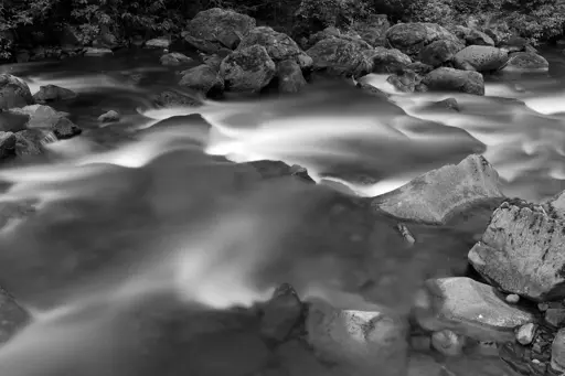 Abstract photo of water flowing over rocks in a shallow creek.