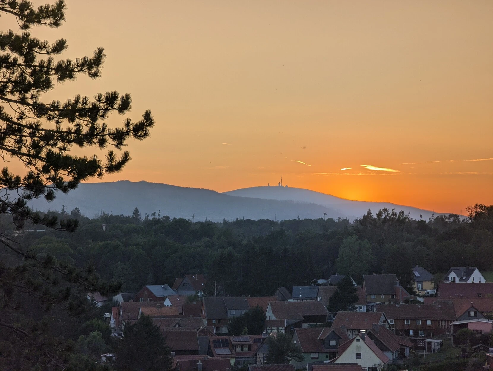 The silhouette of Brocken Mountain, as seen from the east, with the sun going down behind it.

In the foreground the town of Elbingerode is visible.