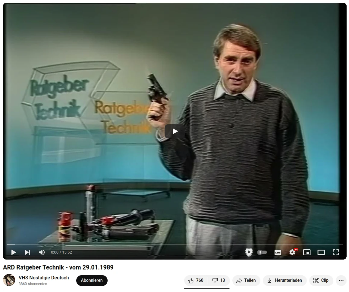 Bernd Leptihn, der Moderator von "Ratgeber Technik" steht mit einer Schusswaffe in der Hand vor einem Tisch mit Pfeffersprays und Schlagwerkzeugen. Im Hintergrund sieht man die Kulisse von "ARD Ratgeber Technik" aus dem Jahr 1989.