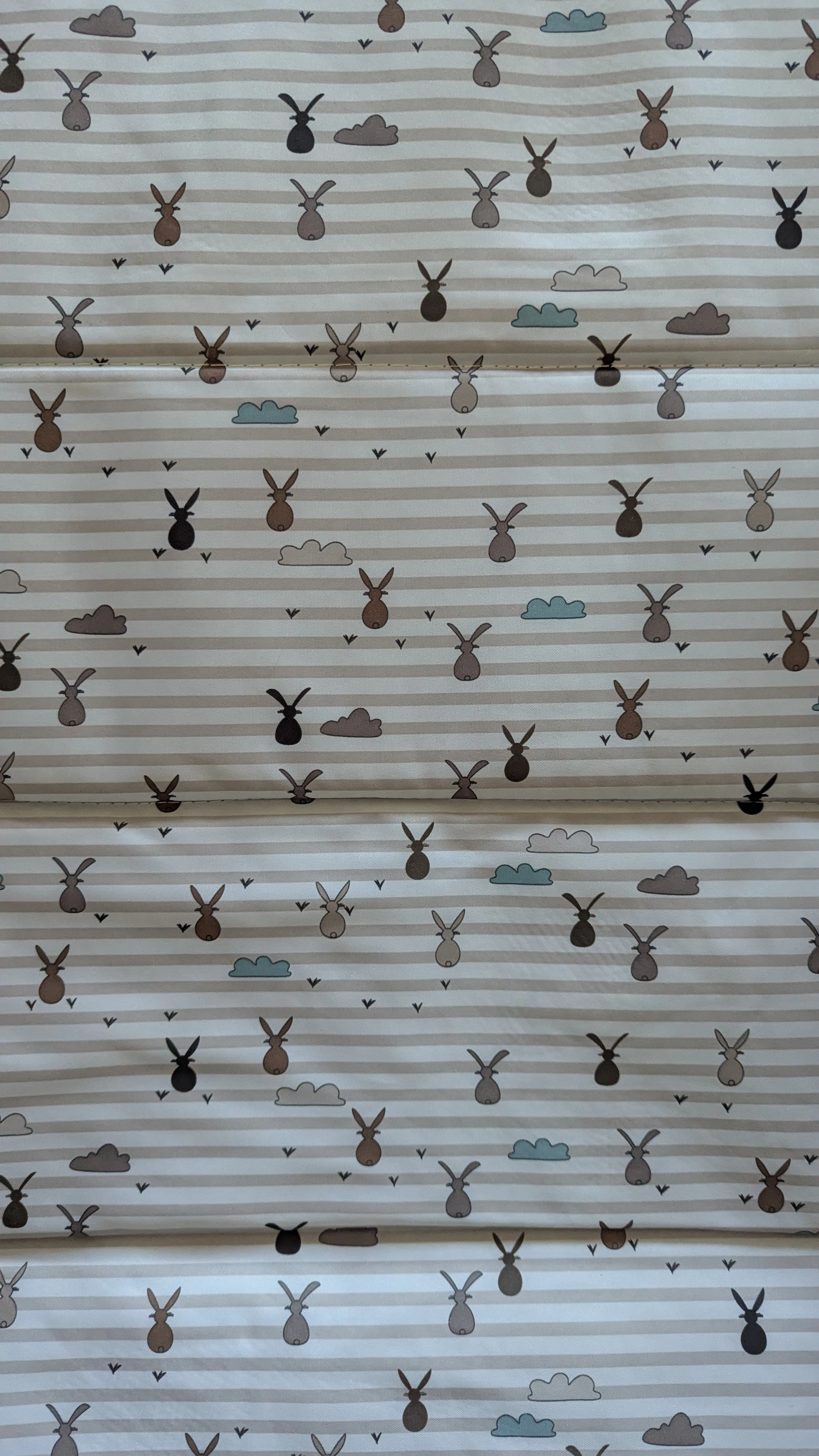 A close up of a mattress patterned with stripes, clouds, and stylized hares 